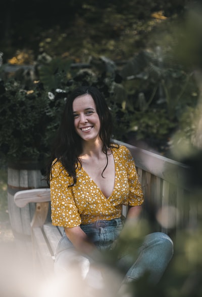 Wearing yellowish-white dot shirt and blue denim jeans woman sitting on a white wood floor
